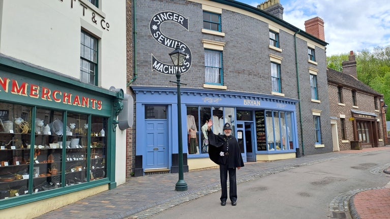 A costumed storyteller dressed as a Victorian policeman waving to welcome visitors to Blists Hill Victorian Town.
